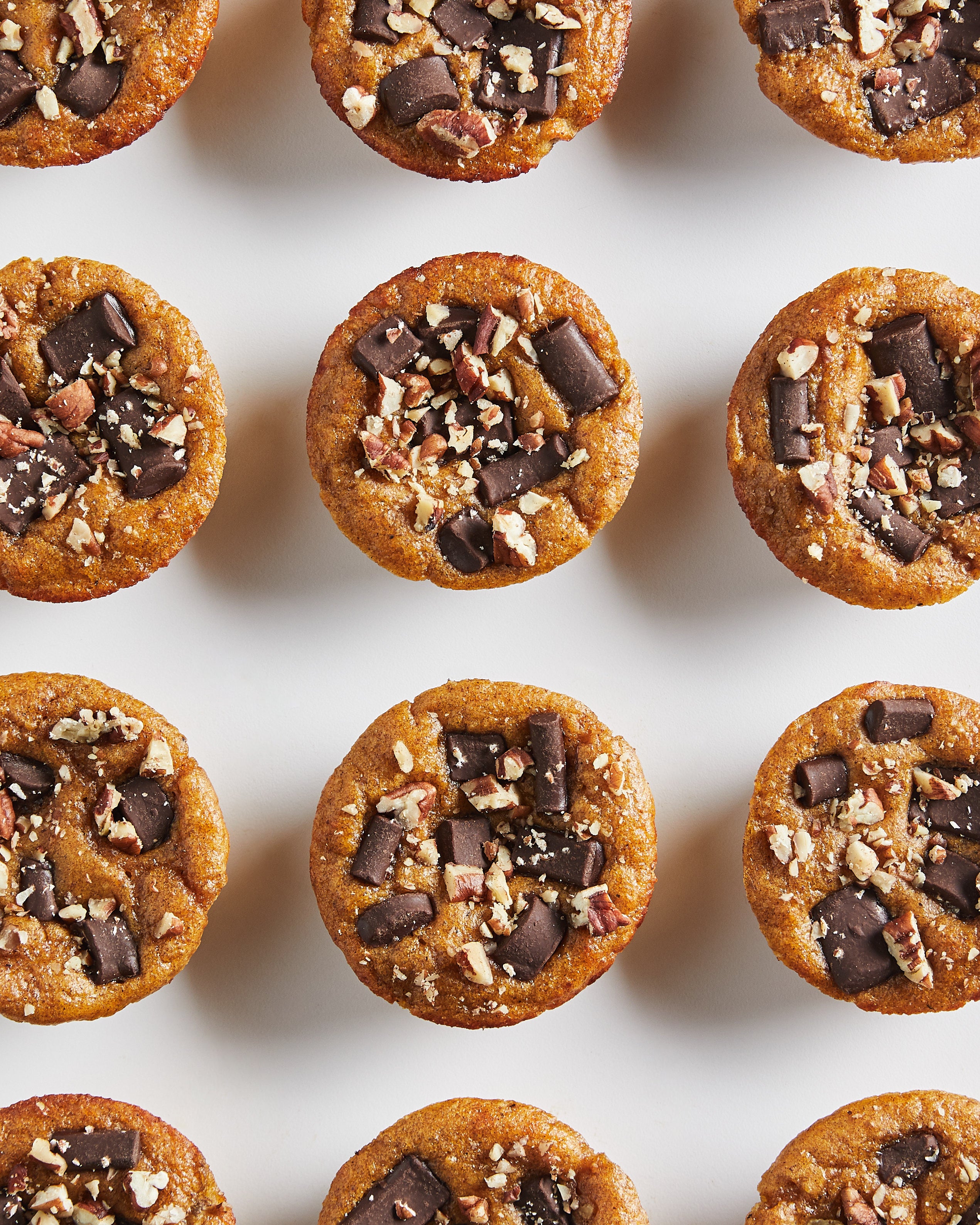 Row of small dessert bites with chocolate and nuts on a white background