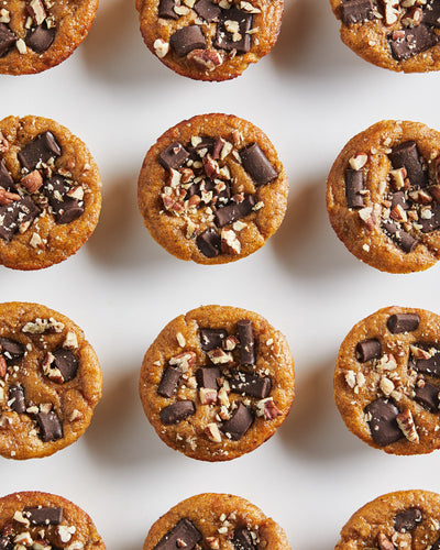 Row of small dessert bites with chocolate and nuts on a white background